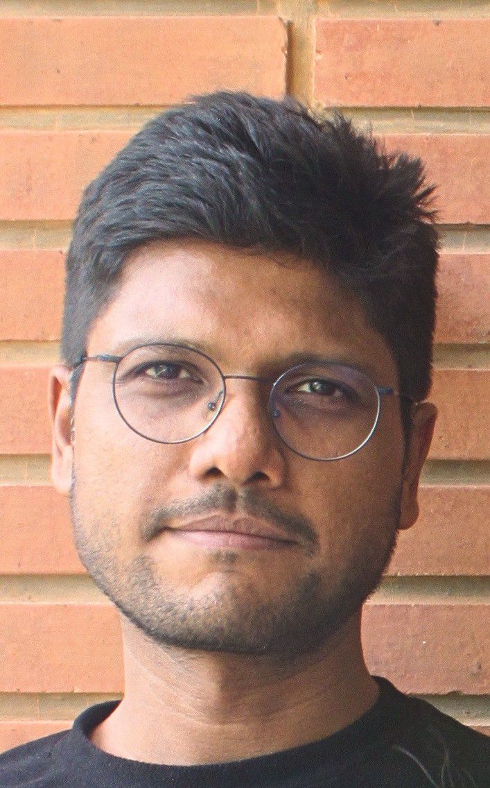 Portrait of Anurag against a warm brick wall.