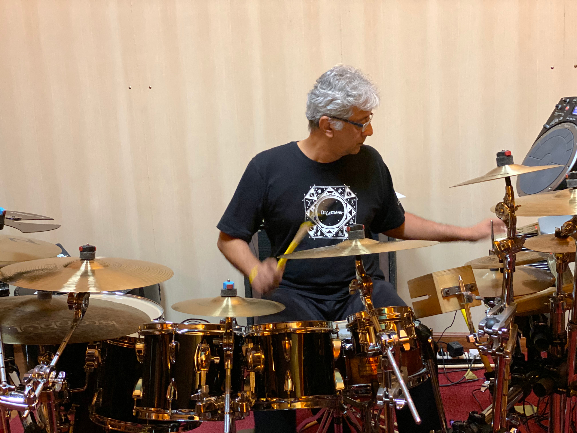 Roberto mid-stroke at a gold-finish drum kit during rehearsal.