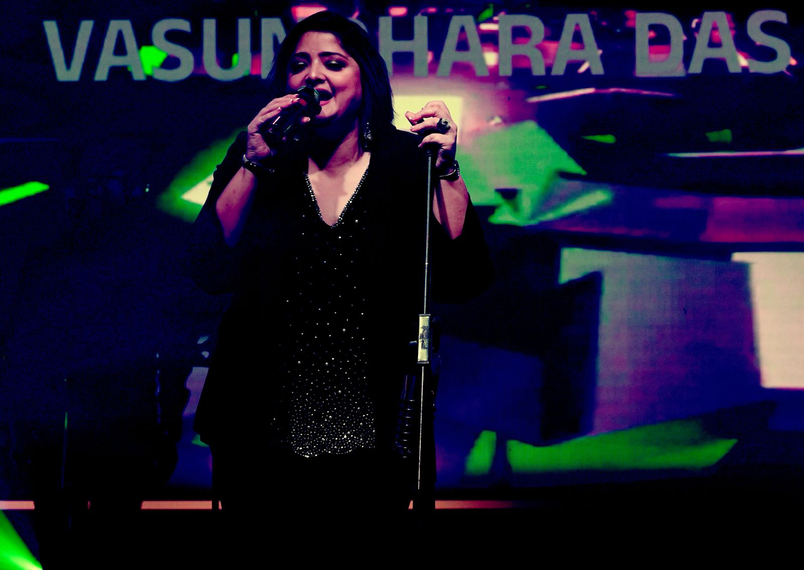 Vasundhara Das at the microphone, name projected behind.