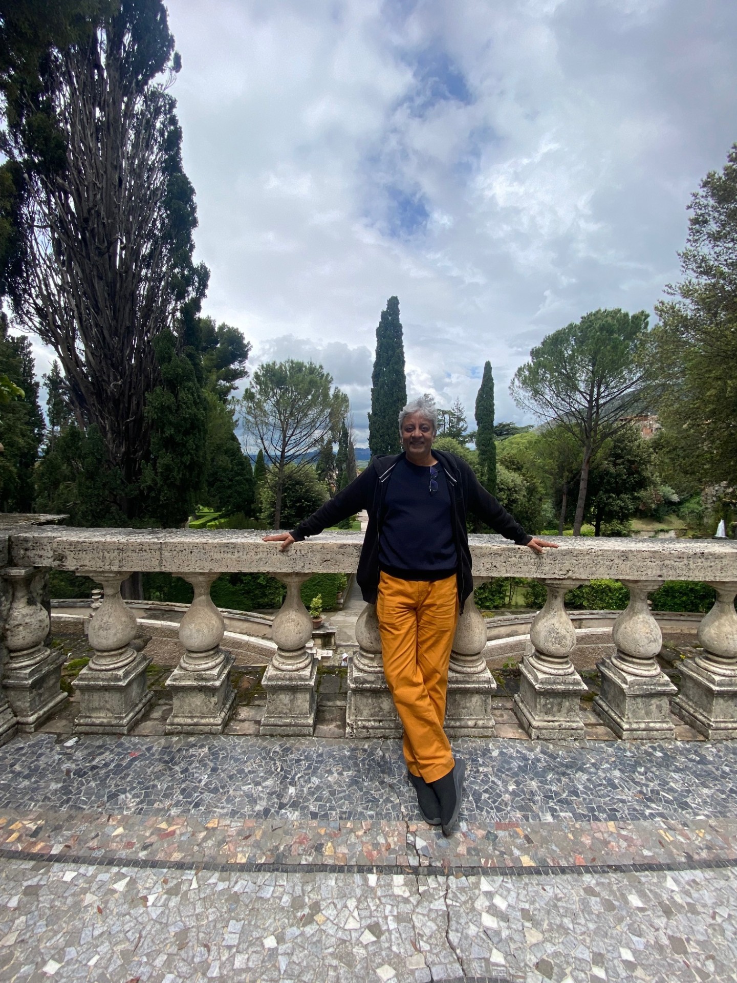 Roberto resting on a stone balustrade overlooking an Italian garden.